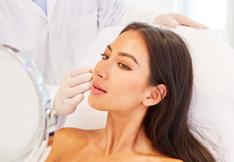 Woman with smooth glowing skin looking at herself in the mirror during a consultation