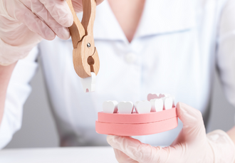 photo of a model mouth with a person removing the model teeth